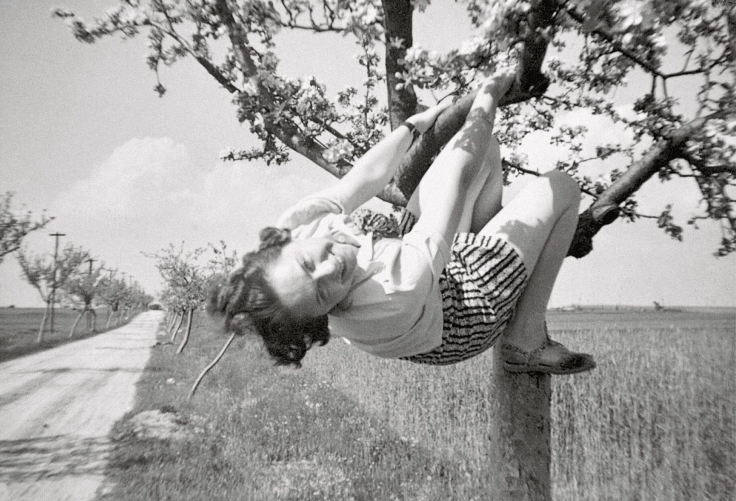 a black-and-white snapshot of a woman in a tree