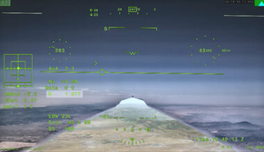 NASA’s X 59 eXternal Vision System digital display shows green flight data overlaid on the forward scenery as the aircraft flies supersonic. Numerical indicators, horizon references, and a Mach number readout are visible on the screen.