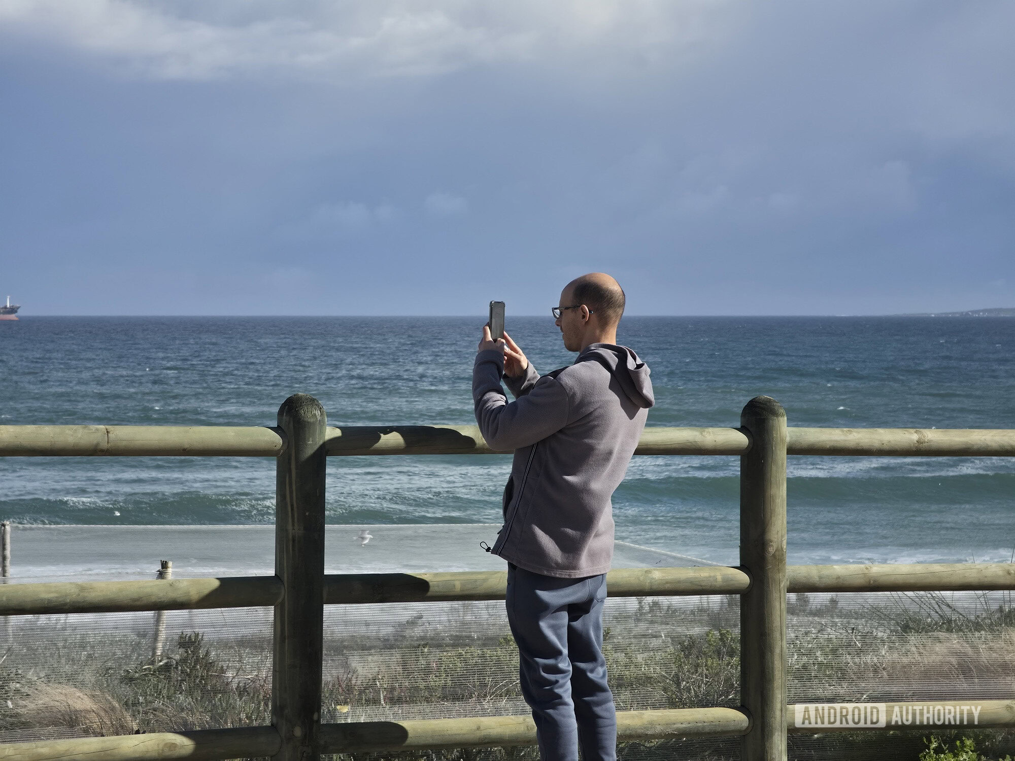 zoomed in photo of man taking a photo on a beach promenade