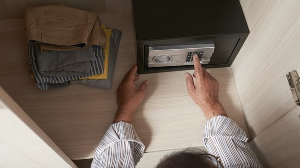 Hands of senior man entering secret combination when opening safe in hotel room