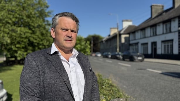 A man stands in front of a row of houses
