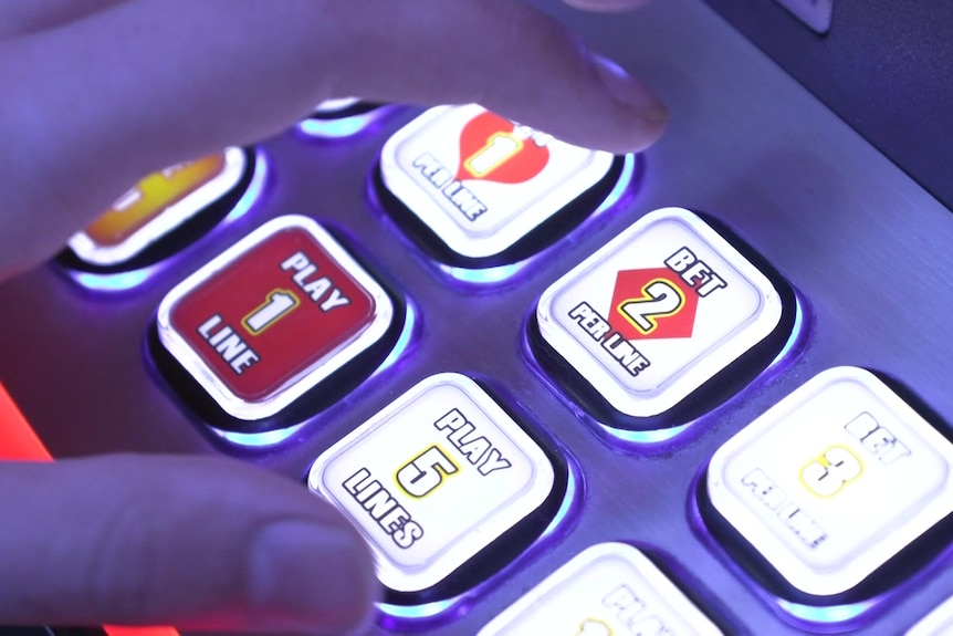 the finger of a person hovering above a poker machine about to hit one of the buttons