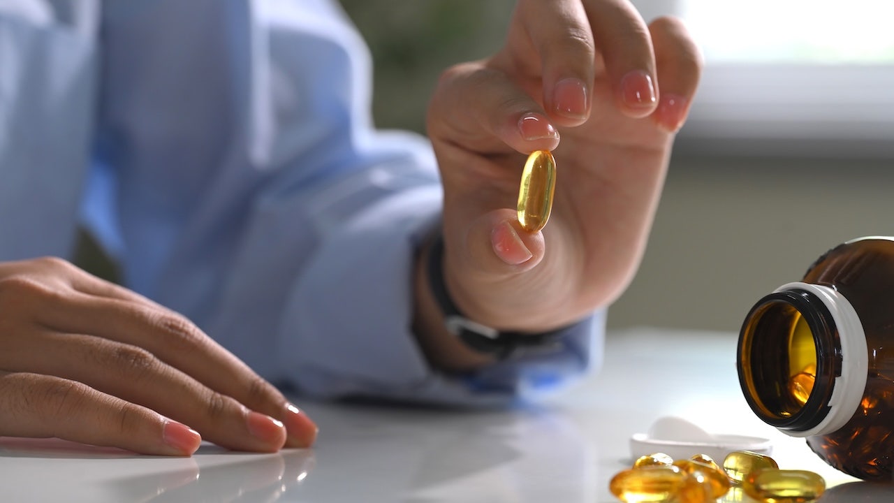 Hand holding a softgel fish oil capsule