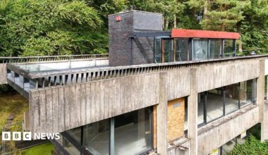 A brutalist studio in the Borders made of cement and glass which is in severe decay with windows boarded up