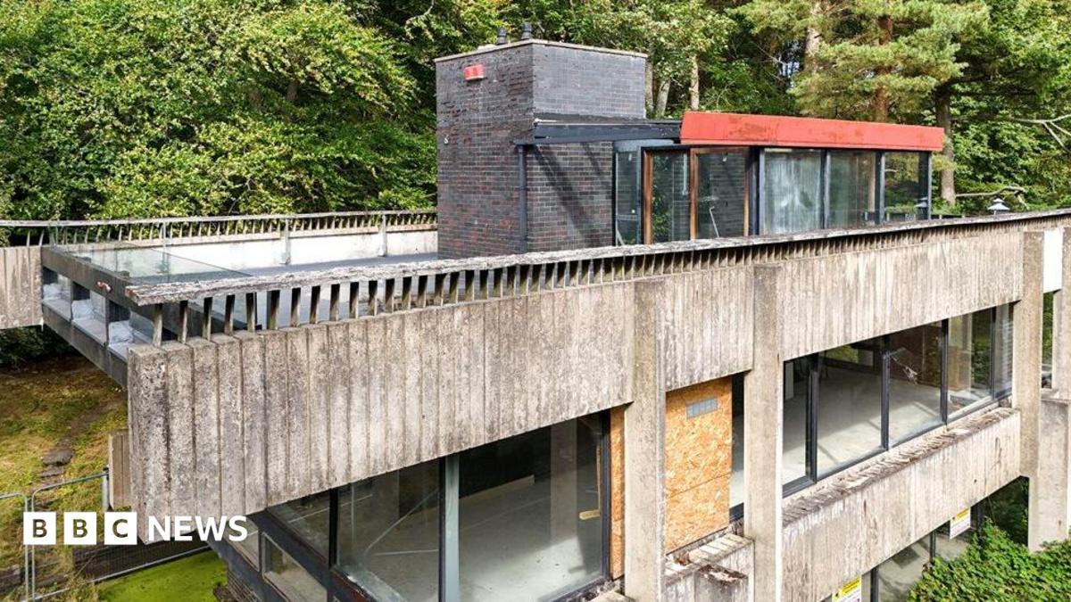 A brutalist studio in the Borders made of cement and glass which is in severe decay with windows boarded up