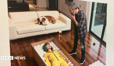 A picture of a piece of art generated by AI. There is a man in jeans and a checked shirt standing over a woman with green hair in a yellow jumpsuit in a box. There is a bulldog lying on the sofa.