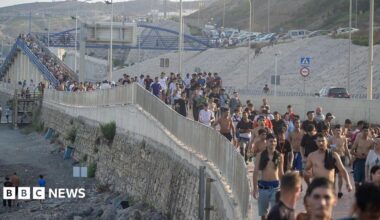 Dozens of migrants walking on a coastal path