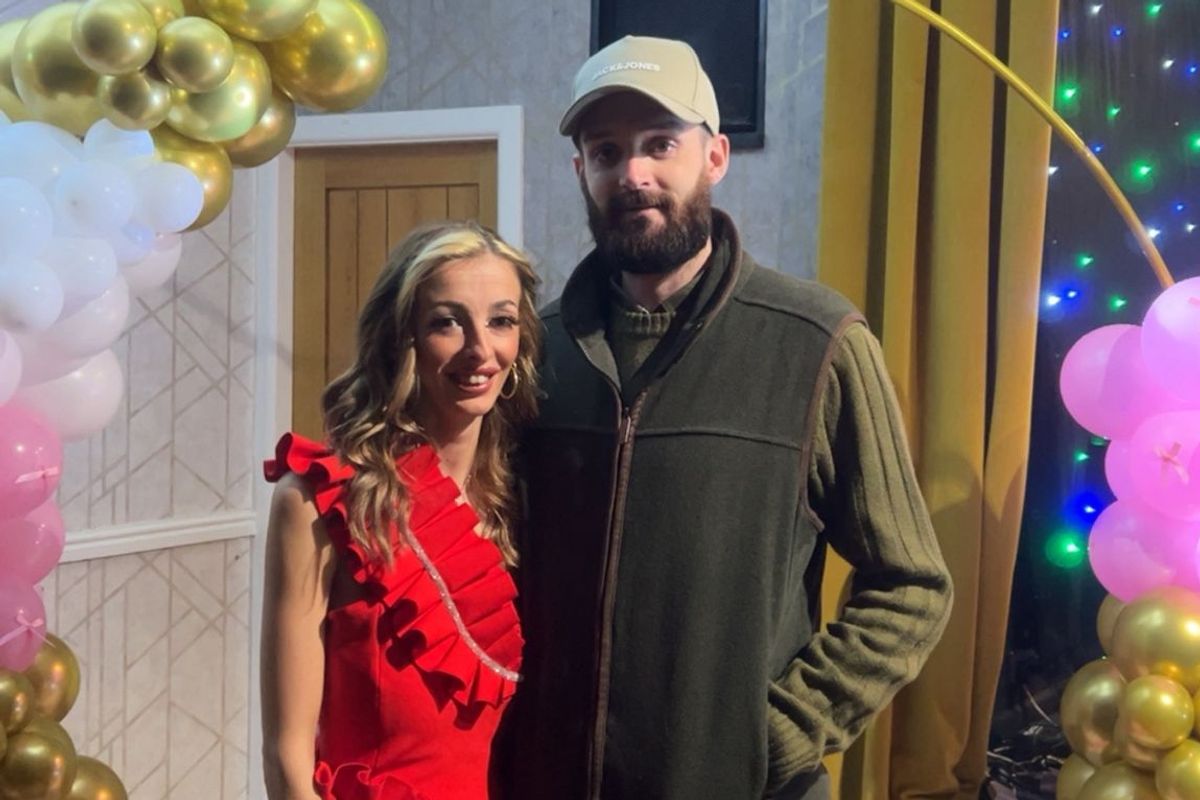 Courtney Reen and Josh Grant stand in front of balloons