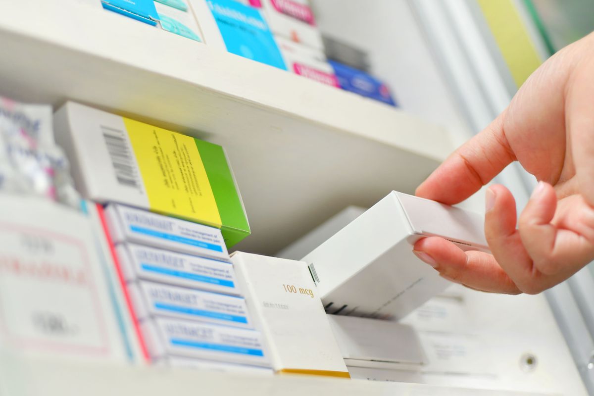Closeup pharmacist hand holding medicine box in pharmacy drugstore.