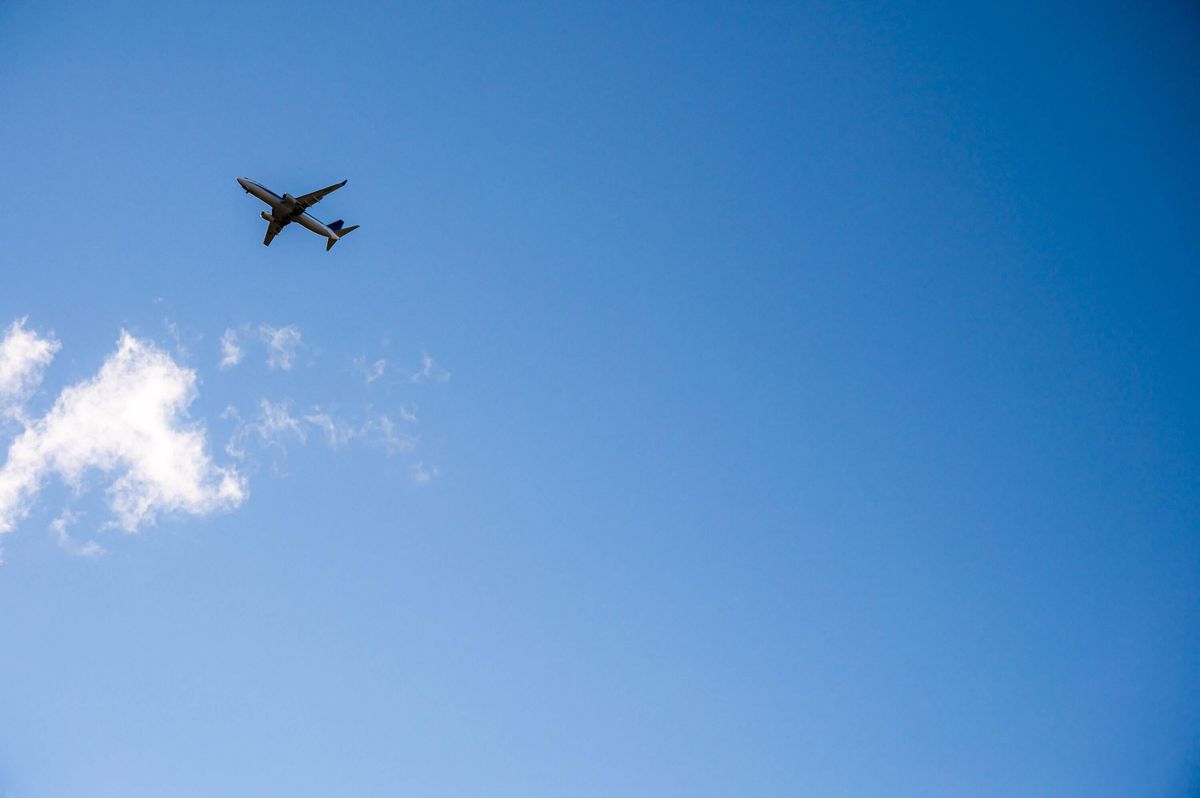 Commercial Airplane Flying Through Blue Sky with White Clouds