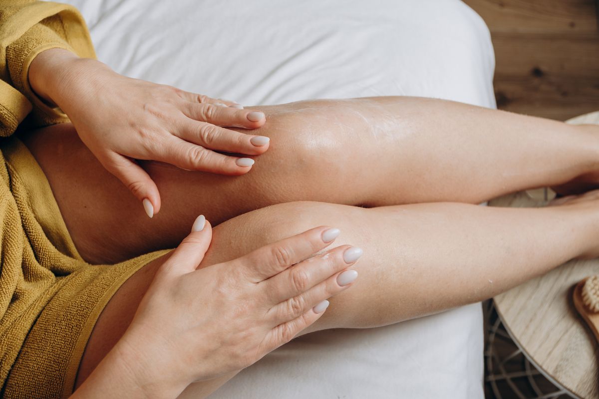 skin care and body care routine woman applies moisturizing or anti-cellulite or anti-aging cream to the skin of her thighs, daily skin care after a shower