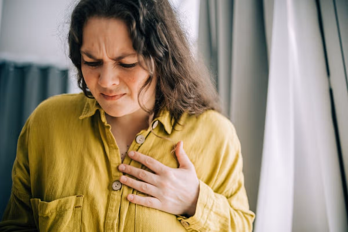 Woman suffering from chest pain holding hand over heart