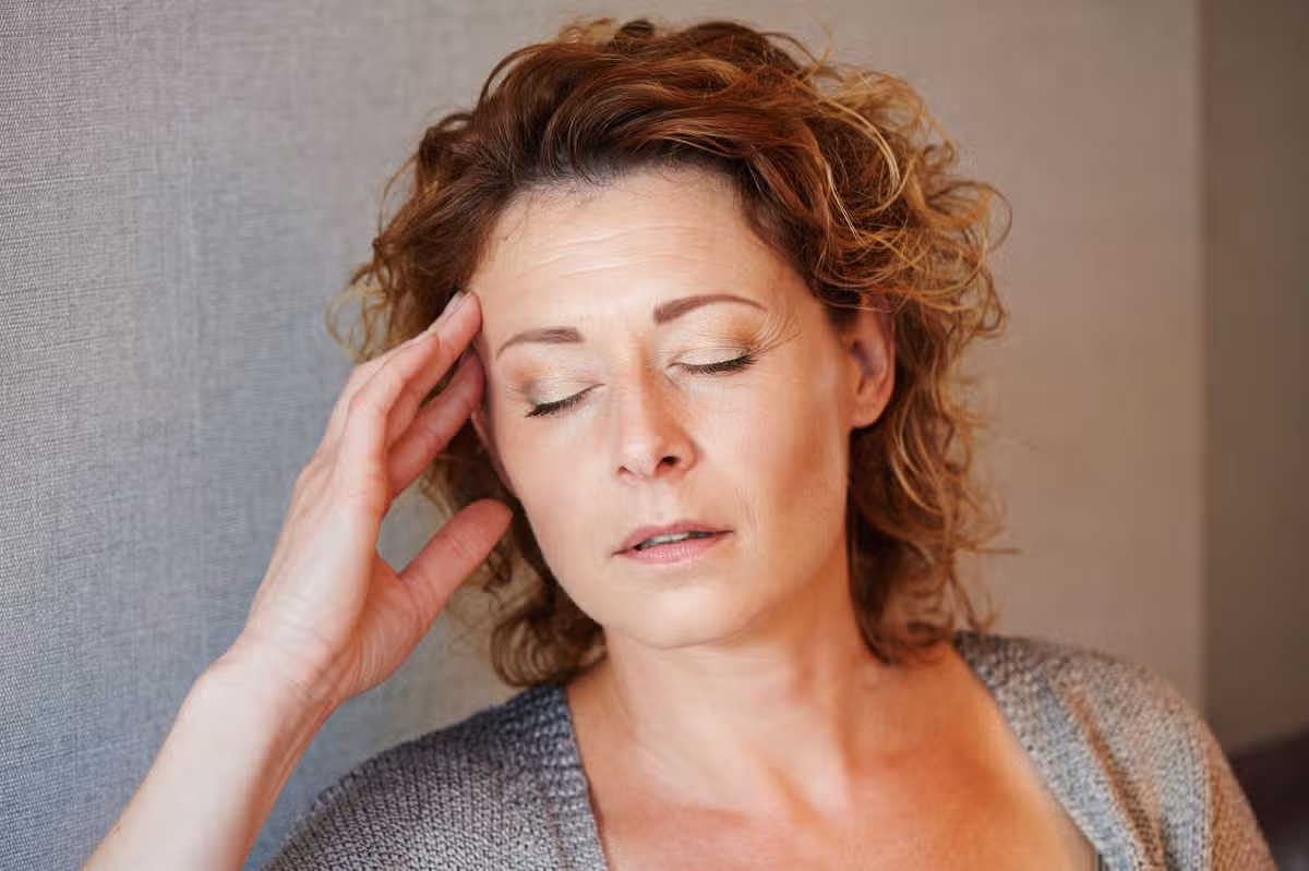 Close up portrait of middle aged woman with hand to head in pain