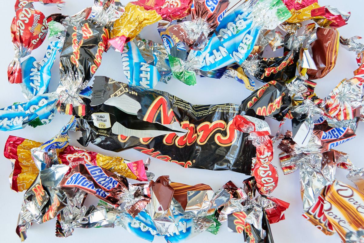 London, UK - February 20, 2020: Torn wrappings of a mix of popular candy bars, in mini sizes, with a big Mars candy bar in the middle.