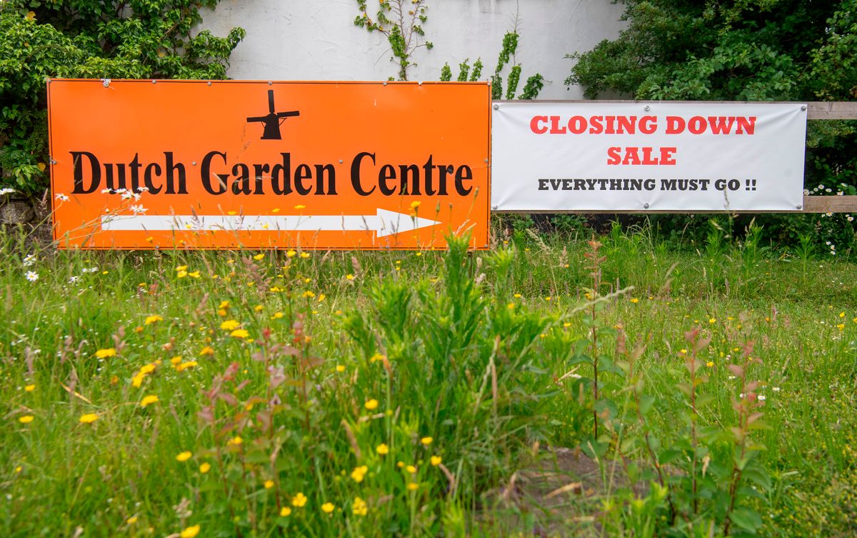 Signage for Dutch Garden Centre in black and orange with windmill logo joined by a closing down sing next to it at  Dutch Garden centre, Cardiff, which is closing after 50 years. 