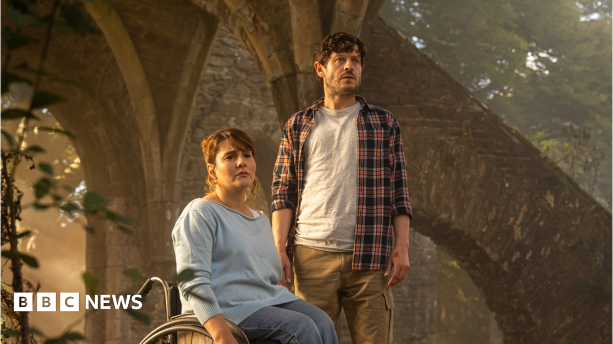 Ruth Madeley and Iwan Rheon in the new TV drama series. They both look concerned and are inside the ruins of an old building with trees behind.