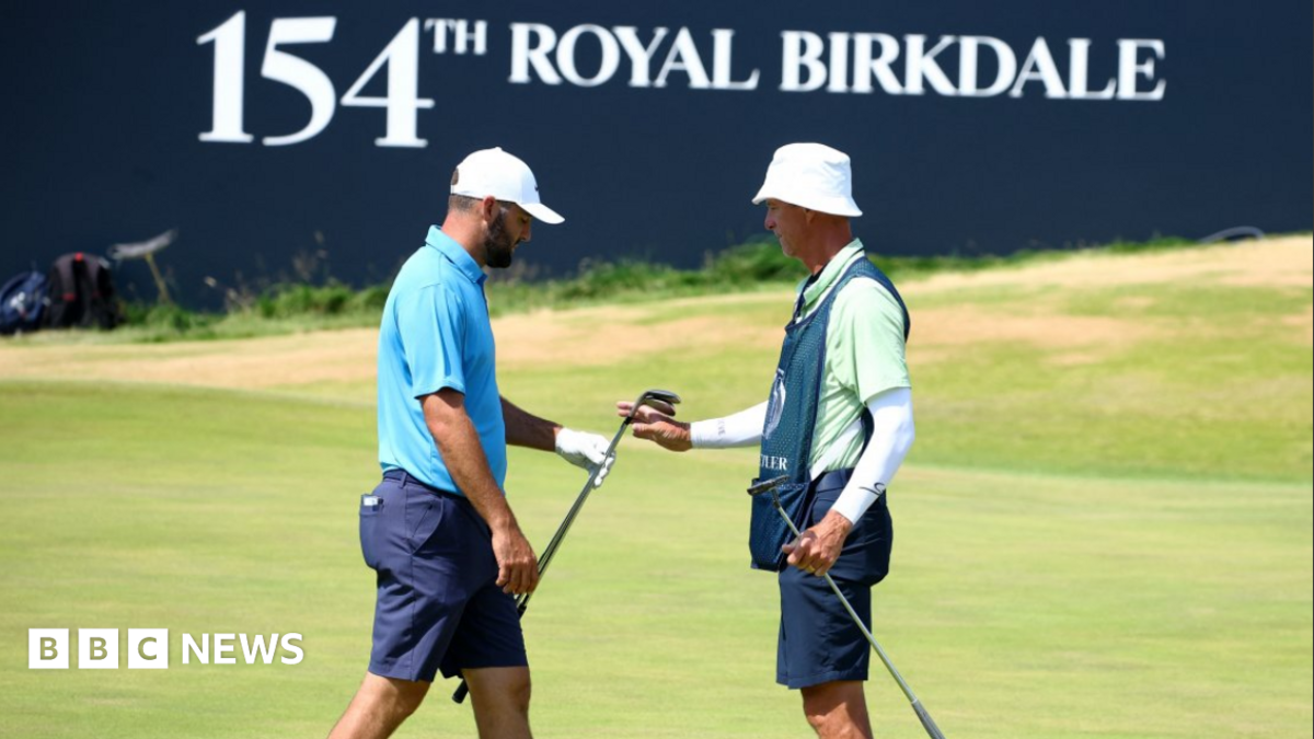 Two men on a golf course in front of a sign reading: '154th Royal Birkdale'.