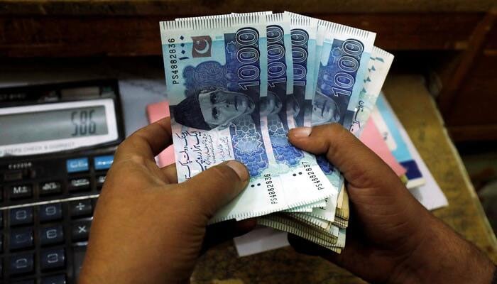 A trader counts Pakistani rupee notes at a currency exchange booth in Peshawar, Pakistan December 3, 2018. — Reuters