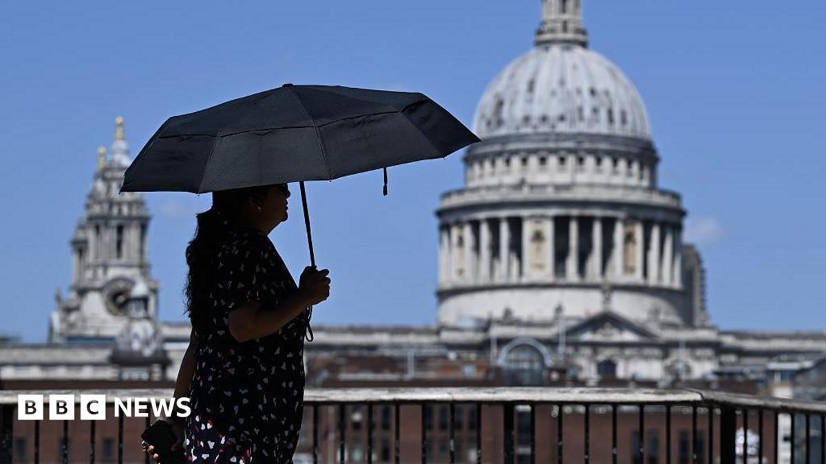 A woman walks under an umbrella past St Paul's Cathedral in London during the heatwave.