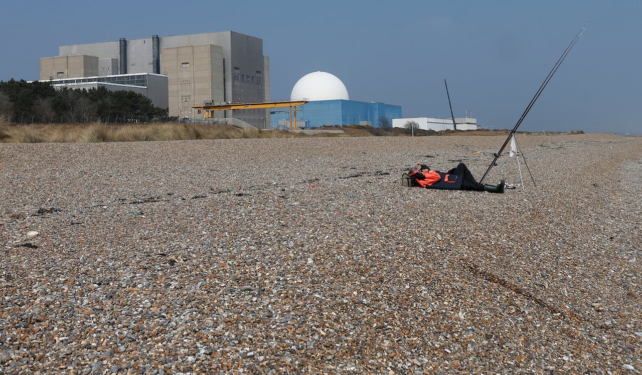 A fisherman takes a nap on the beach outside the Sizewell nuclear power station in Suffolk, England. The Sizewell C reactor will be built in this complex.