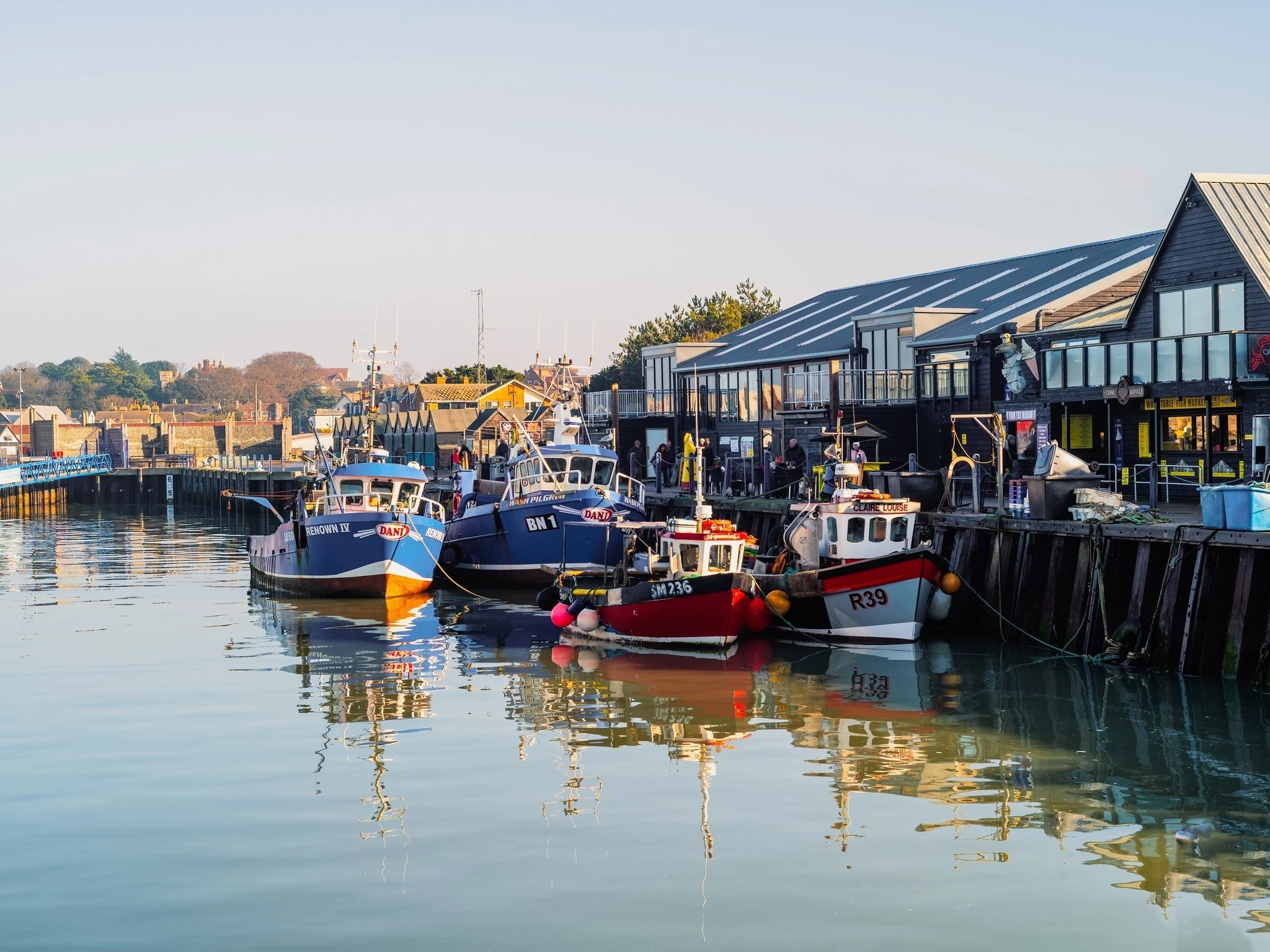 Colourful fishing boats in Whitstable harbour on a bright winter day.