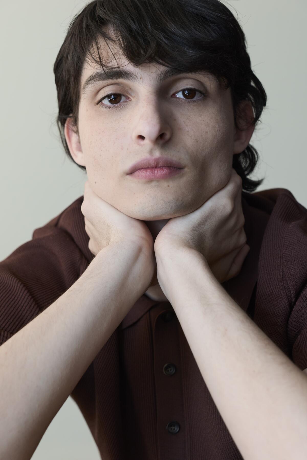 Finn Wolfhard posing with head in hands