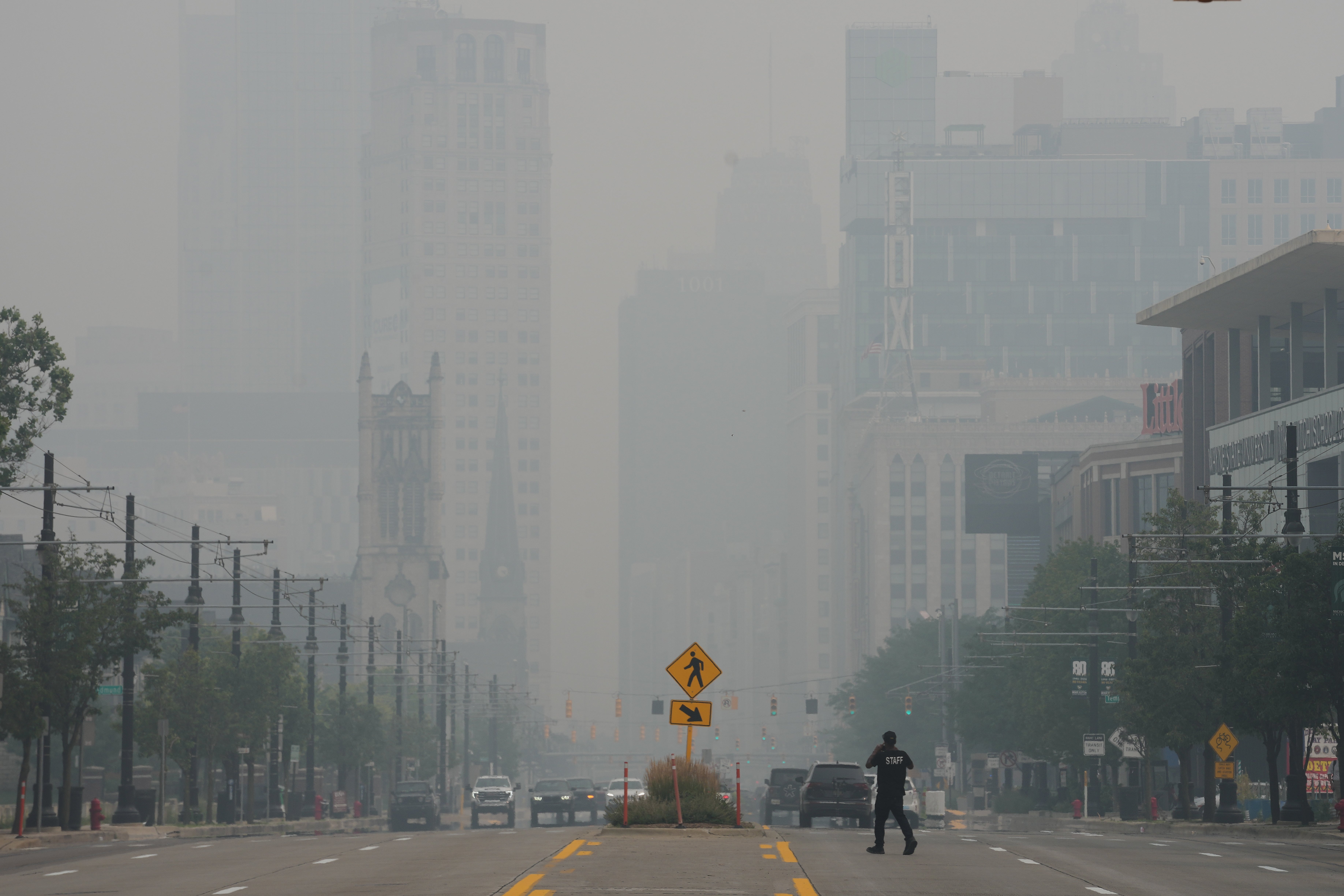 A pedestrian crosses the street as the Detroit city skyline is obscured during poor air quality due to smoke from Canadian wildfires Thursday, July 16, 2026, in Detroit. A group of Michigan lawmakers sent a letter to the Canadian government demanding it do more to address its wildfires and the smoke they produce