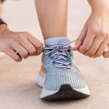 Close-up view of female jogger tying laces of her sport shoes before running exercise routine. Motivation, healthy lifestyle and fitness concept.