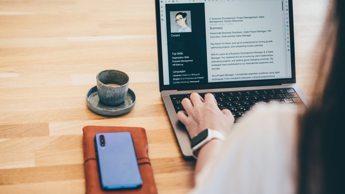 Young business woman searching for job online. Woman writing resume on laptop.