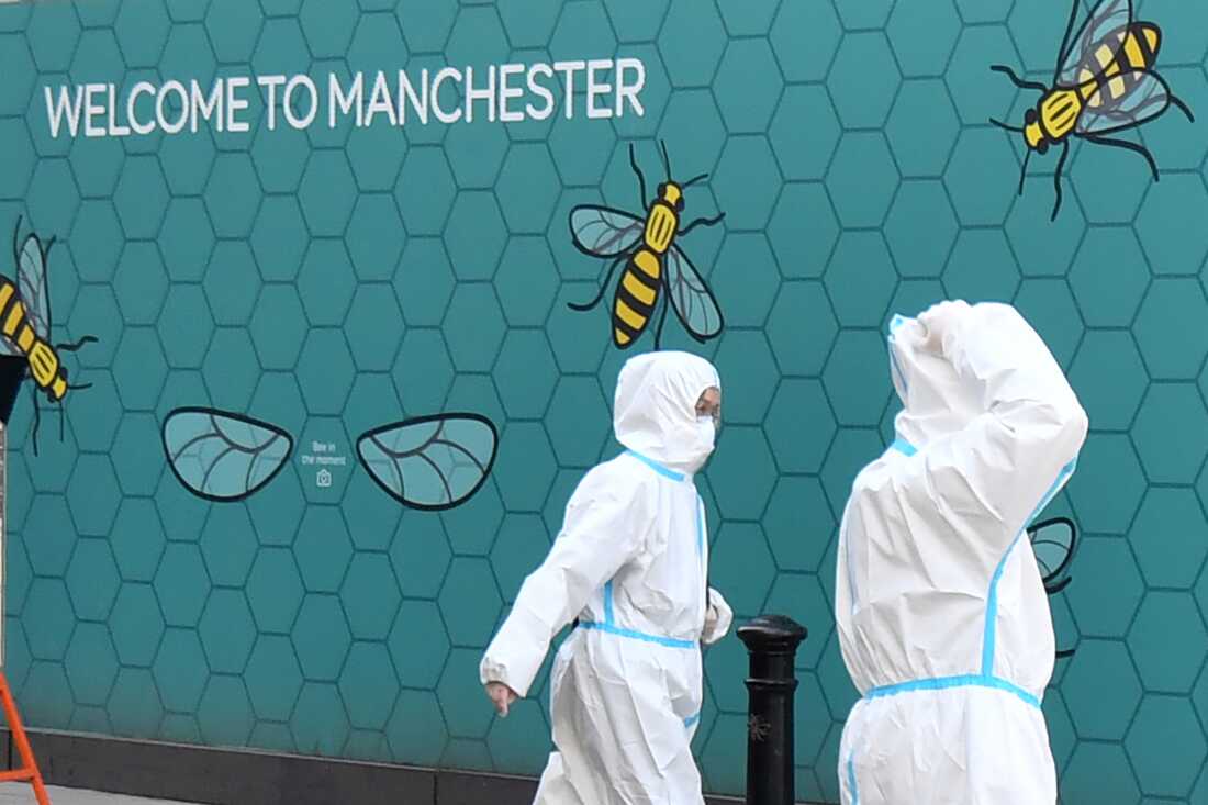 People wear protective suits as they walk along Market Street in the near-deserted city center in Manchester, England, on April 15, 2020, during the nationwide lockdown to combat the coronavirus pandemic.