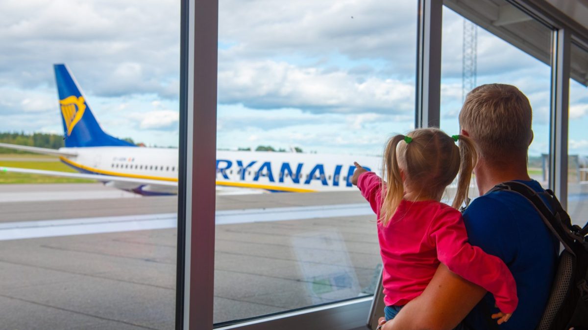 Skavsta Airport, Nykoping, Sweden - September 12, 2019: Father and daughter looking out through the window of the airport concourse at the Ryanair airplane waiting for the boarding
