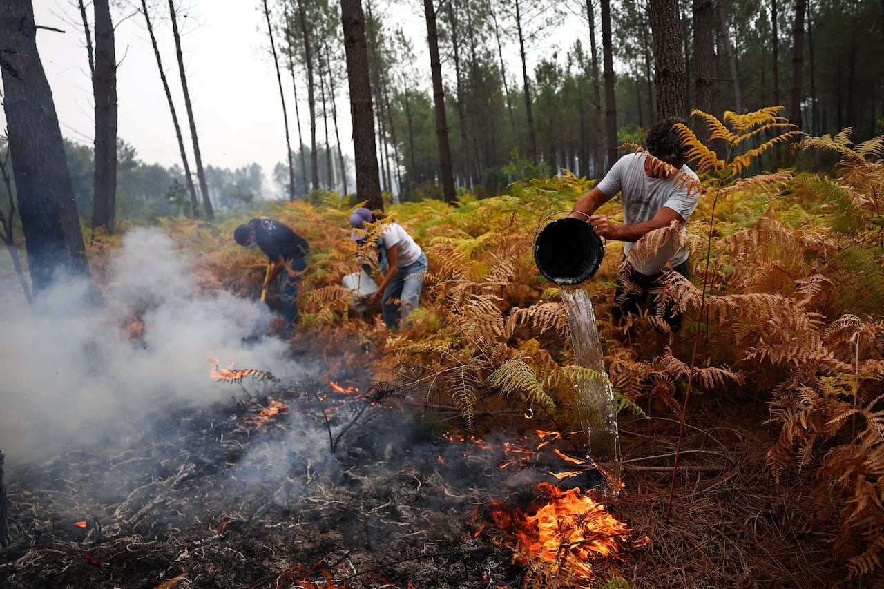Residents pour bowls of water on a fire.