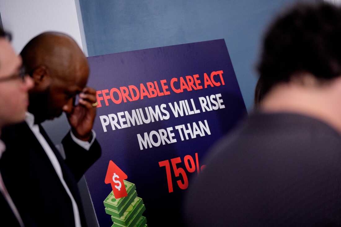 A restaurant owner with his head bowed and his hand to his brow stands next to a sign that reads "Affordable Care Act Premiums Will Rise More Than 75%."