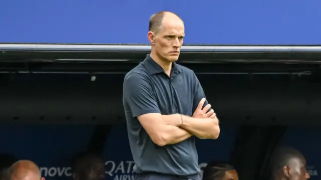 England manager Thomas Tuchel with his arms folded. He is wearing a navy blue shirt.