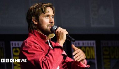 Ryan Gosling speaking into microphone on stage at San Diego Comic-Con