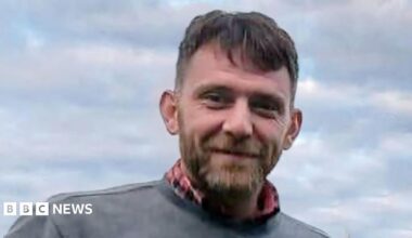 Jim Mair - a man with dark hair and a beard, smiling into the camera