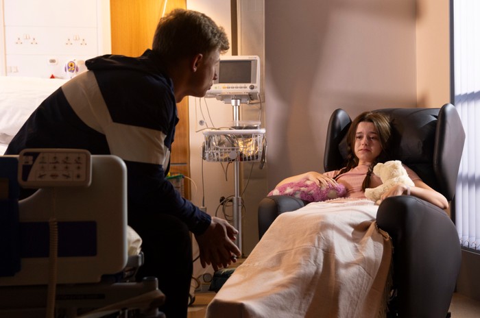 20_07_coro_dylan_03 Dylan sits on a bed nearby Betsy in a hospital chair for Coronation Street.