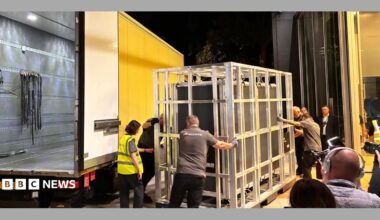 The tapestry arring in a crate being loaded from a yellow van in the middle of the night