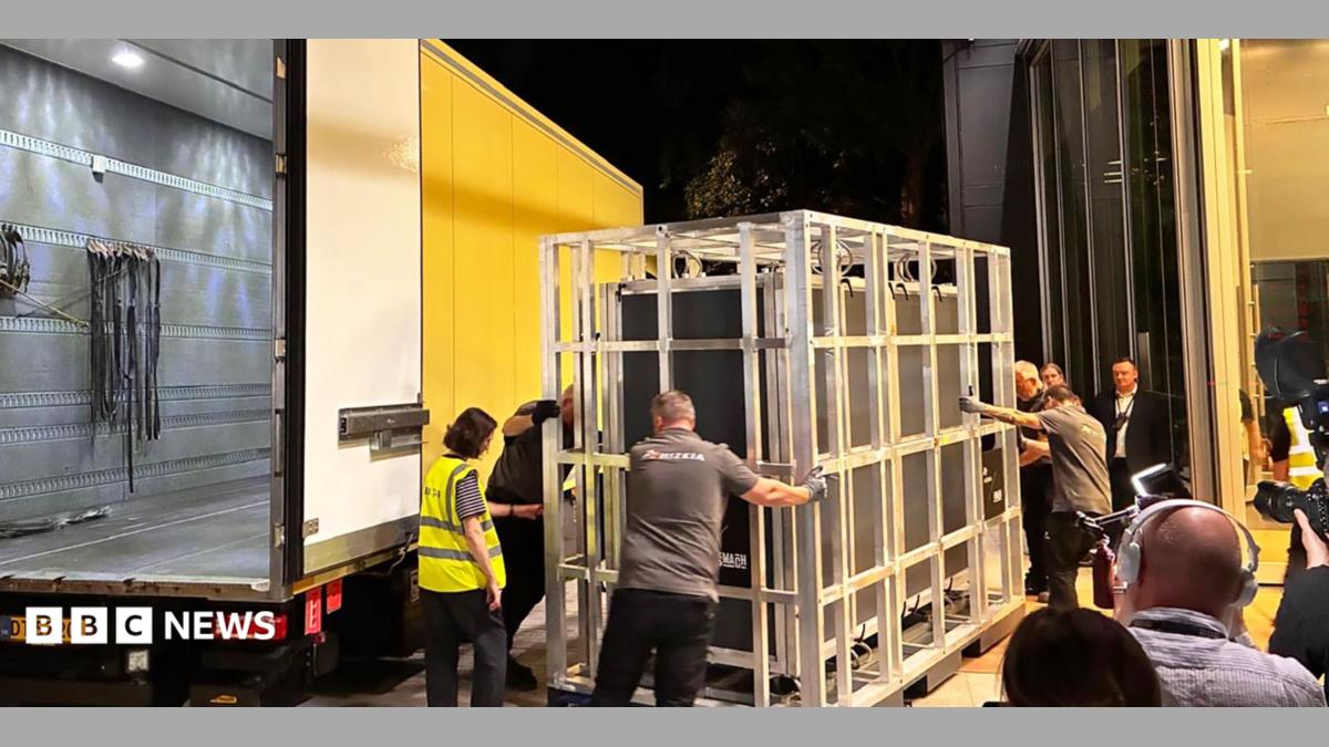 The tapestry arring in a crate being loaded from a yellow van in the middle of the night