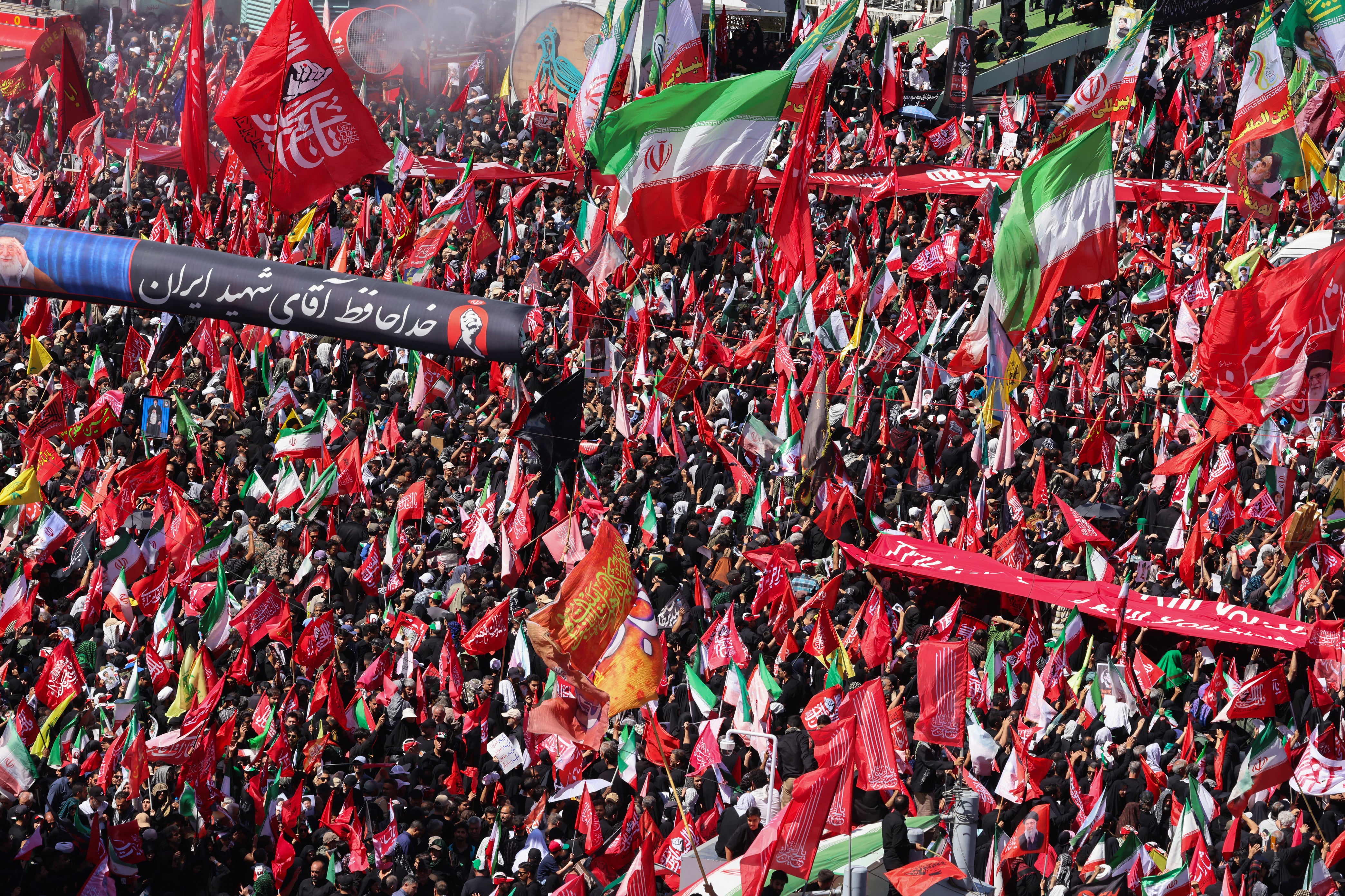 Mourners march with flags and banners during a funeral procession for Khamenei