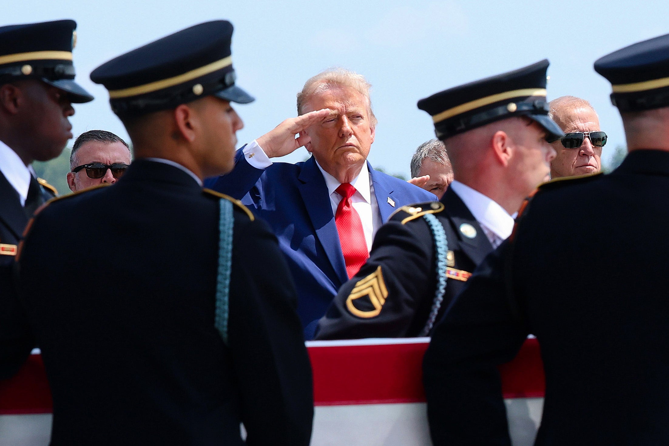 Donald Trump (C) salutes as members of a US Army carry team as they transfer the remains of the killed soldiers