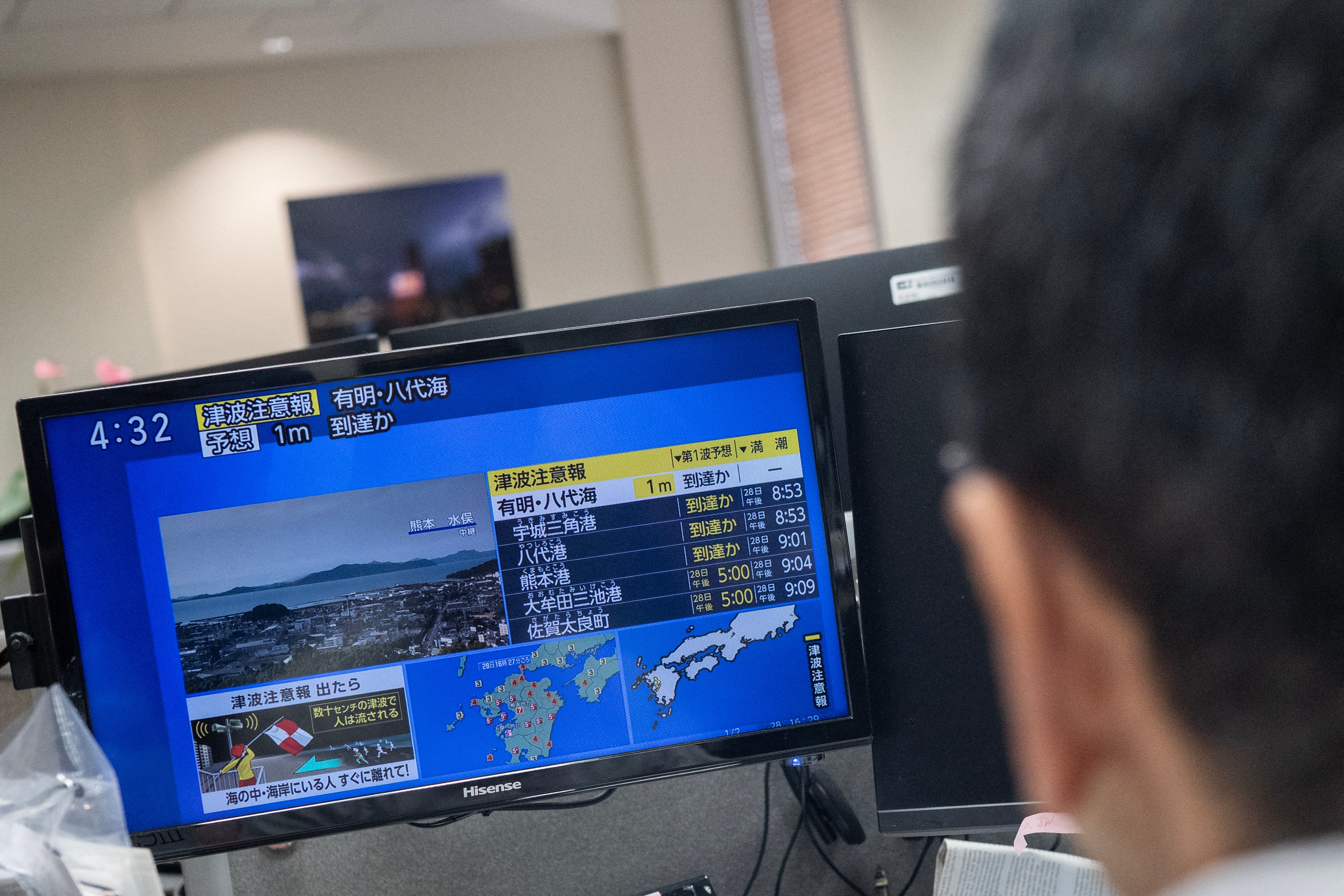 Reporters watch the news showing a large quake and possible one meter tsunami wave in Southern Japan, from an office in Tokyo