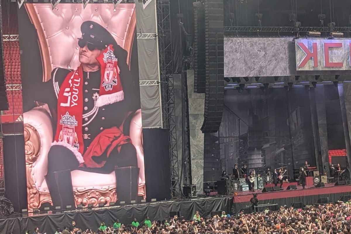 Performer on stage wearing a Liverpool FC scarf
