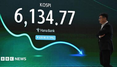A man walks past an electronic screen showing South Korea's benchmark stock index falling by 9.19%.