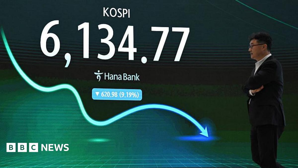A man walks past an electronic screen showing South Korea's benchmark stock index falling by 9.19%.