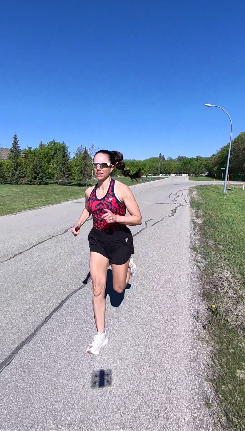 Person running on a sunny road with green trees in the background. Person running on a sunny road with green trees in the background.