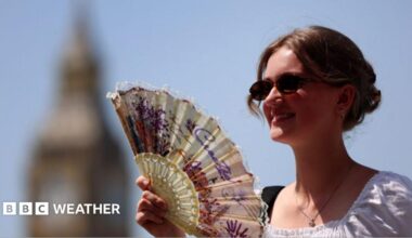 A woman uses a fan in London during a late-June heatwave