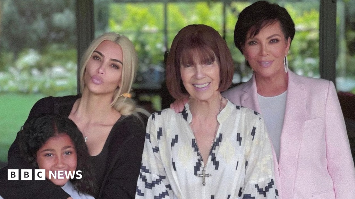 This photo shows Kim, her daughter, Mary Jo and Kris posing together smiling. They are standing by some bright pink flowers.