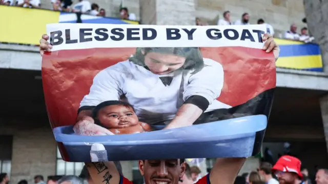 A Spain fan holding a print-out of Lionel Messi and Lamine Yamal