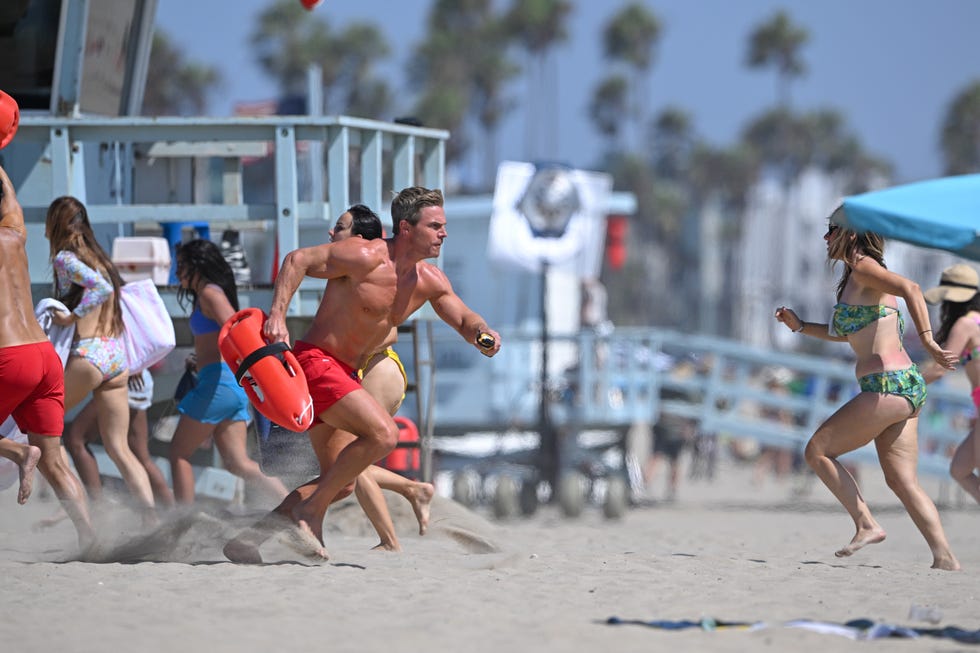 Stephen Amell filming Baywatch in Los Angeles stephen amell runs shirtless on the beach with a red bouyancy aid while filming baywatch in los angeles